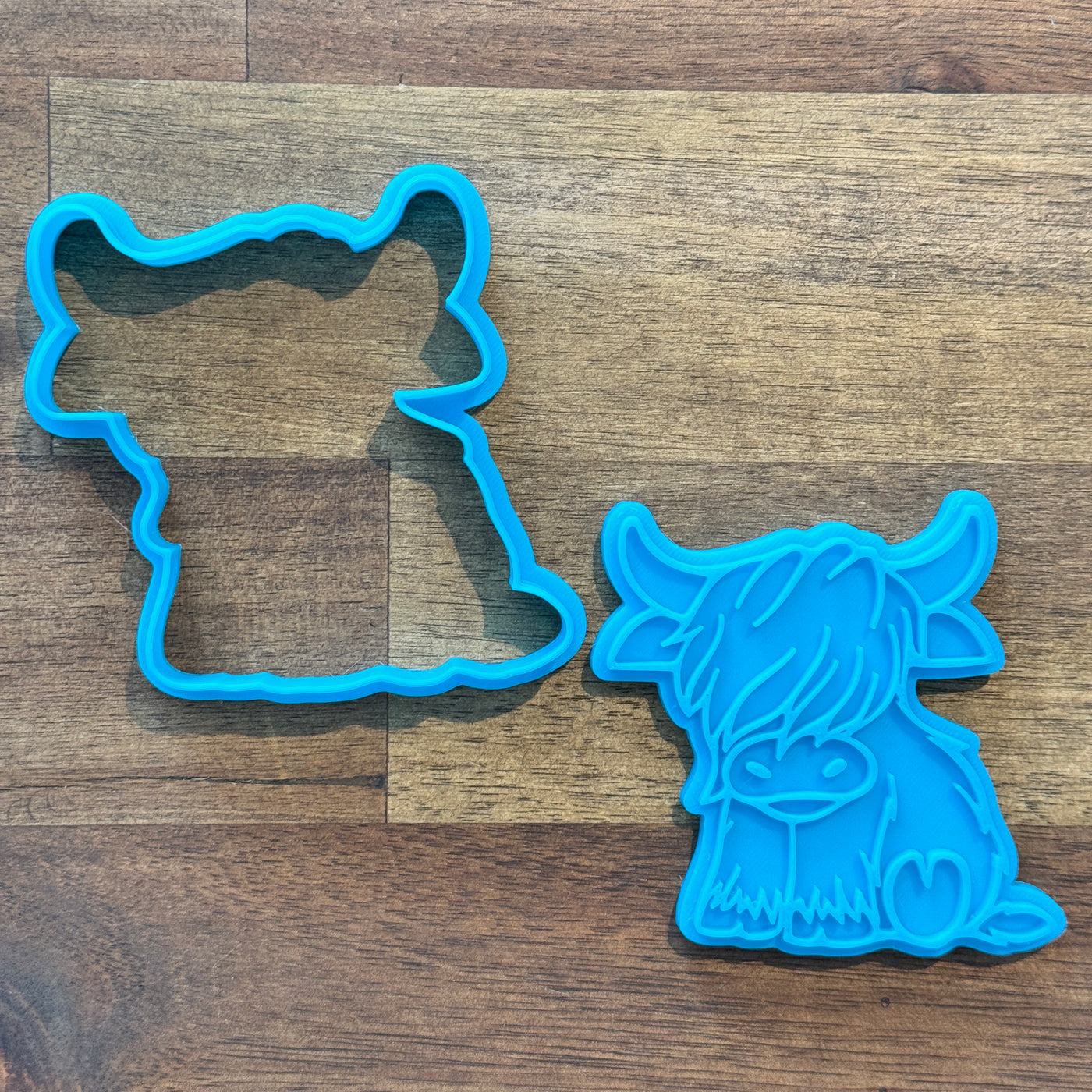 A blue Highland Cow cookie cutter and matching embosser made by Cookie Cutter Central